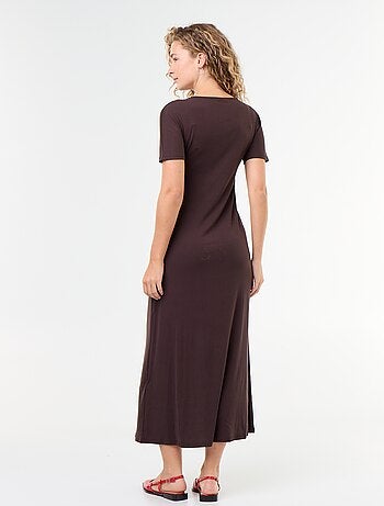 Lange jurk met geplooide pasvorm en gehamerde goudkleurige broche.