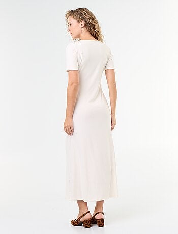 Robe longue coupe plissée et broche dorée martelée.