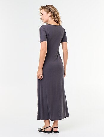 Robe longue coupe plissée et broche dorée martelée.
