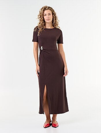 Robe longue coupe plissée et broche dorée martelée.